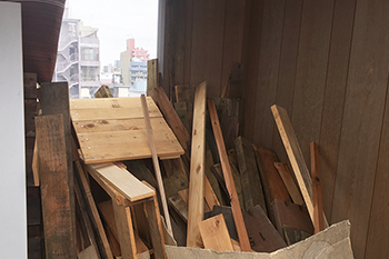 シェアハウスがあるビルの屋上には、以前の入居者が運送会社から入手した物流用木製パレット（すのこのようなもの）などの廃材が置かれている