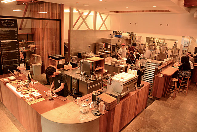 天井が高く、柱の少ない元倉庫は、広いスペースを必要とするチョコレートづくりにうってつけ。二階はカフェスペースとなっていて、若者だけでなく、地元のお年寄りから、子連れファミリーまで、さまざまなお客でにぎわっている