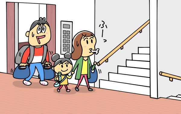 エレベーターを下りて、階段へ向かう荷物をたくさんもった家族