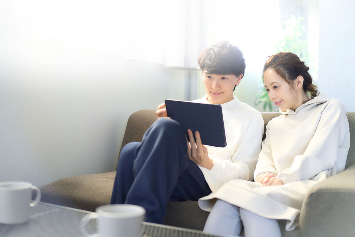 リビングでタブレットを見ている男女