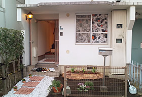 玄関にお手製の花壇を設置。レンガ調タイルも敷き、明るいエントランスに